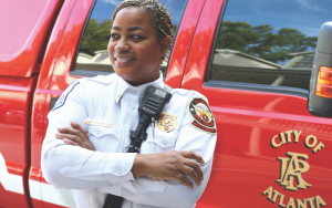 Michelle Middlebrooks standing in her fire uniform in front of a red Atlanta fire truck