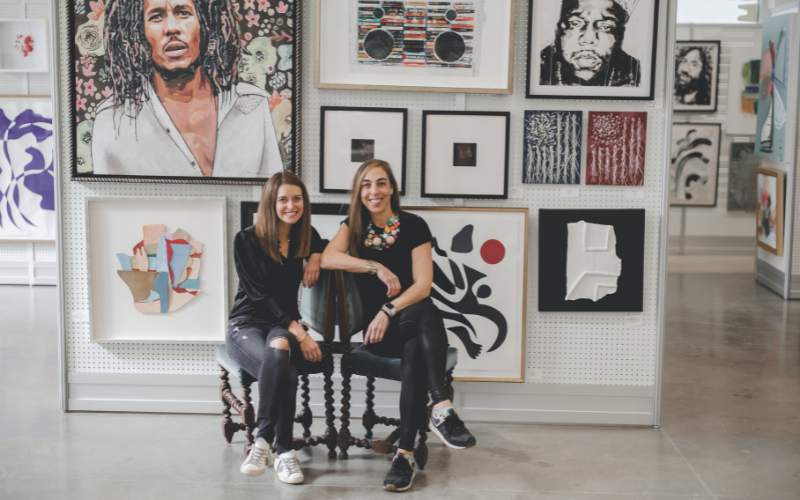 two girls sitting in front of art work