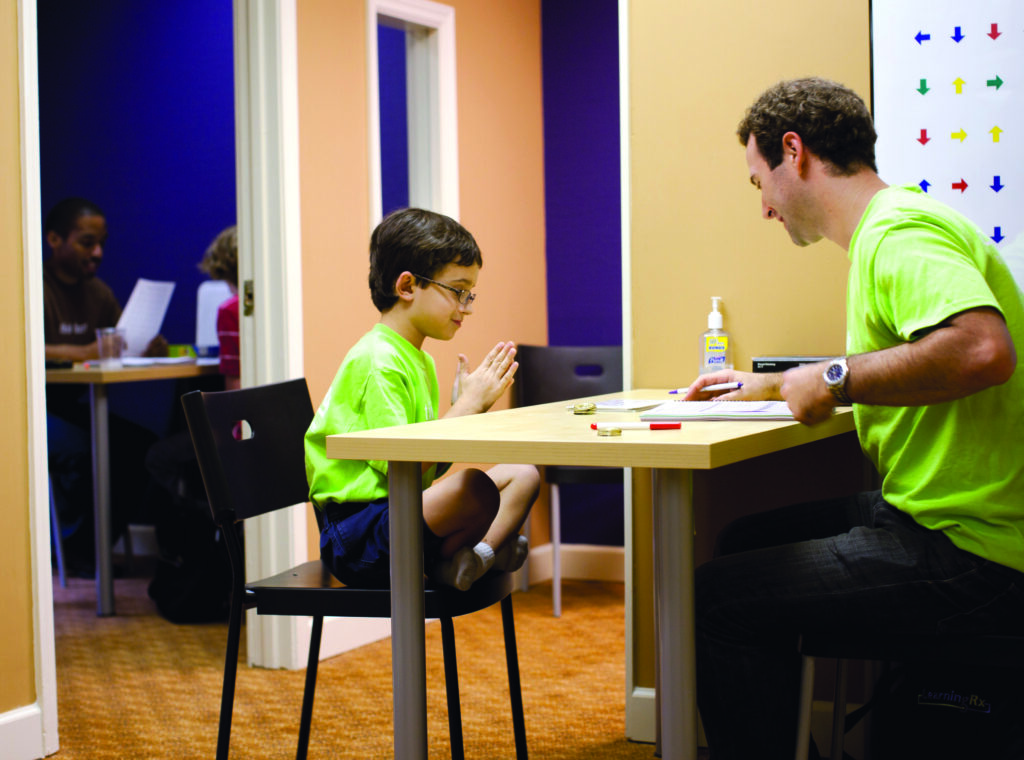 Man tutoring boy in green shirts